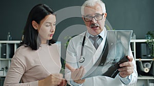 Patient and doctor looking at X-ray image talking indoors in office in hospital