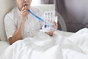 Patient elderly woman using incentivespirometer or three balls for stimulate lung in room