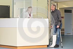 patient with foot fracture stands at the reception of a clinic