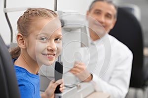 Patient, girl posing with doctor in optician office.