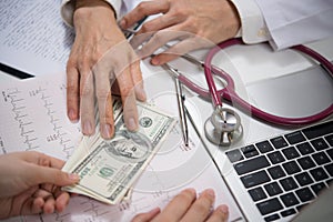 Patient giving money to medical doctor in hospital setting