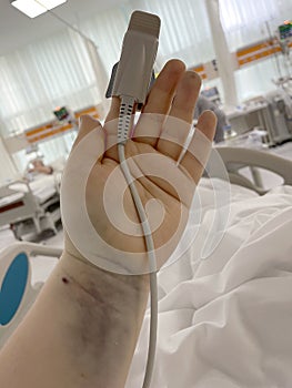 Patient hand with pulse oximetry probe in hospital intensive care unit photo