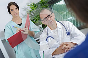 Patient having consultation with nurse writing notes in office