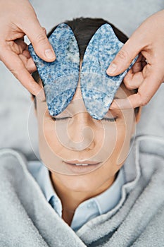 Patient having her forehead massaged with blue spot jasper scrapers