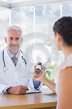 Patient holding a bottle of pills in front of doctor