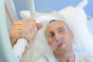 Patient holding hand on hospital bed to recover