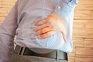 Patient holds right side with his hand in tilted position. Concept photo of pain in right side of abdomen due to diseases of kidn