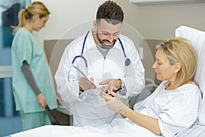 patient in hospital bed signing consent form
