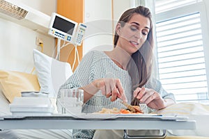 Patient in hospital lying in bed eating meal