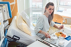 Patient in hospital lying in bed eating meal
