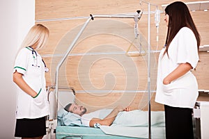 Patient in hospital room next to nurses