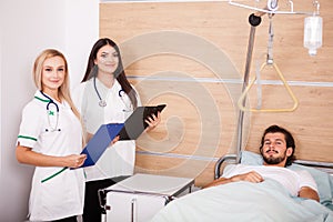 Patient in hospital room next to nurses