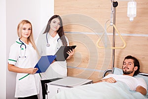 Patient in hospital room next to nurses