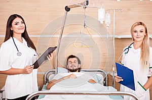 Patient in hospital room next to nurses