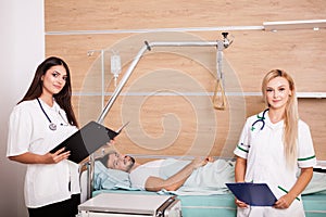 Patient in hospital room next to two nurses