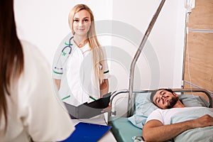 Patient in hospital room next to two nurses