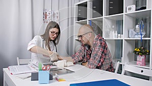 A patient with an injured wrist in the doctor`s office.The doctor examines the patient`s wrist. The doctor examines an x