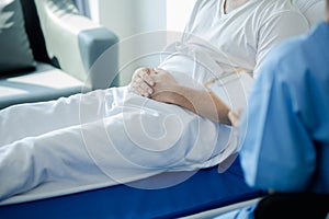 Patient on an inpatient hospital bed with a doctor examining and asking for information about the symptoms in order to diagnose