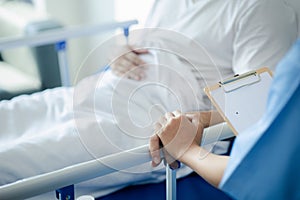 Patient on an inpatient hospital bed with a doctor examining and asking for information about the symptoms in order to diagnose