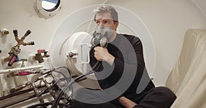 Patient inside white hyperbaric chamber after trauma