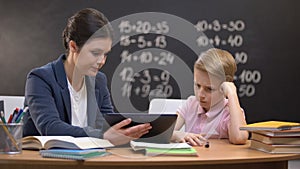 Patient lady teacher explaining subject on tablet, schoolboy does not understand