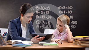 Patient lady teacher explaining subject on tablet, schoolboy does not understand