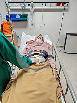 Patient laying on bed receiving medical treatment from nurse at hospital