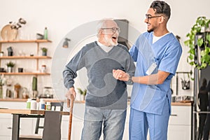 Patient leaning on the cane supported by a young nurse
