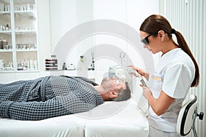 Patient lies on a cosmetology couch during the photorejuvenation procedure