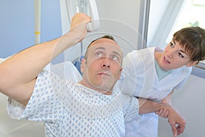 Patient lifting himself out bed with hoist nurse helping