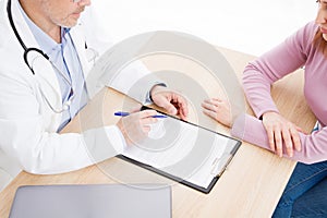 Patient listening intently to a male doctor explaining patient symptoms or asking a question as they discuss paperwork together