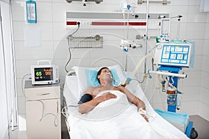 Patient lying in hospital bed surrounded by medical equipment