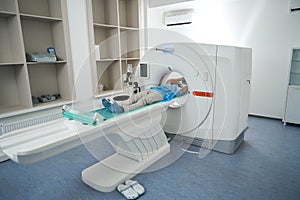 Patient in medical center lies in the chamber of tomograph