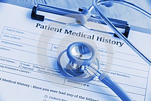 Patient medical history on a clipboard with stethoscope and a blue ballpoint pen.