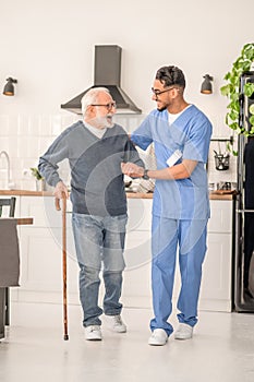 Patient moving around the kitchen assisted by his in-home nurse