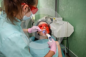 Patient with open mouth sitting in dentist chair in glasses