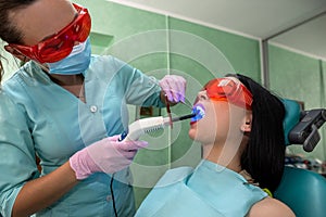 Patient with open mouth sitting in dentist chair in glasses
