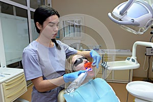 Patient with open mouth sitting in dentist chair in protective glasses