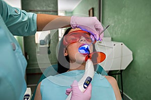 Patient open mouth sitting in dentist chair in protective glasses