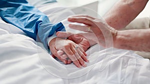 Patient, person and hand holding on hospital bed for support or empathy for health hope, diagnosis or virus. People