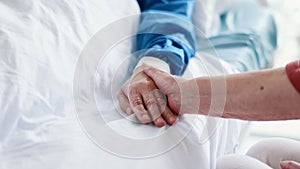 Patient, person and holding hands on hospital bed for comfort for health problem for medical support, love or empathy