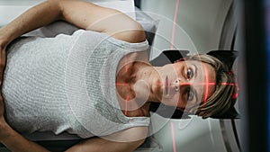 Patient positioned for head scan with laser alignment in CT scanner photo