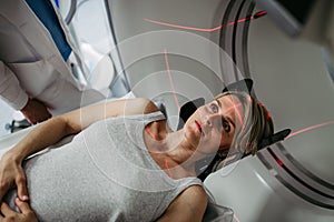 Patient positioned for head scan with laser alignment in CT scanner photo