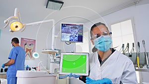 Patient pov of dentist analisyng x-ray using tablet with green screen