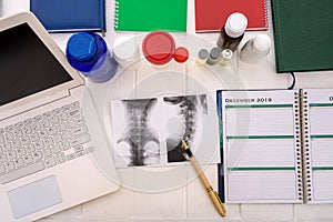 Patient`s x-ray on table with notepad, pills and bottles