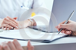 Patient signing medical contract. Female doctor explains how to fill medical form.