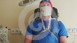 Patient sits at doctors and the doctor adjusts wires in cap for EEG. Health care.