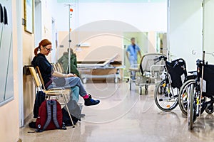 Patient sitting in hospital ward hallway waiting room with iv