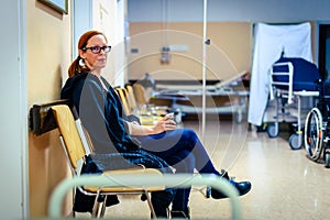 Patient sitting in hospital ward hallway waiting room with iv.