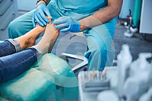 Patient sitting on the medical chair while doctor looking to the foot
